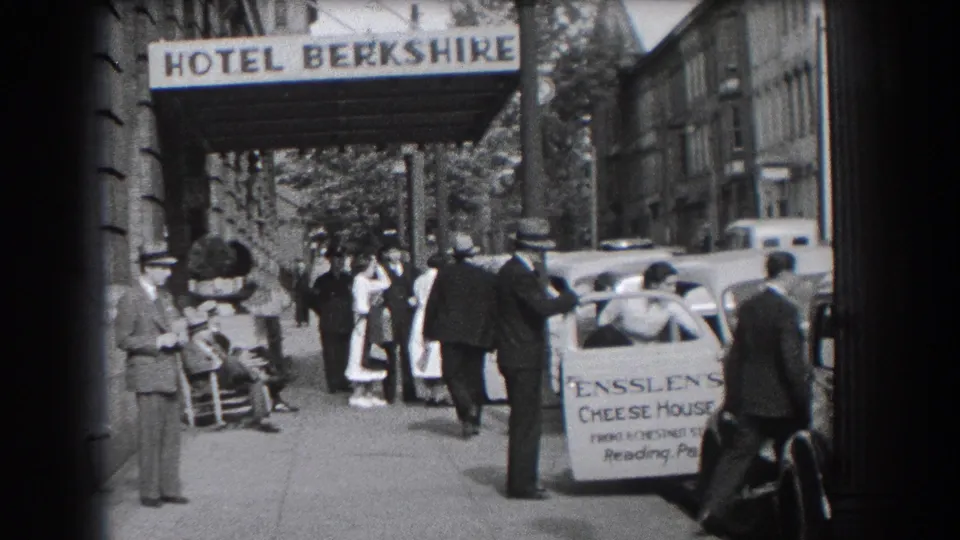 1938 Reading, Pennsylvania street scene showing pedestrians, a hotel entrance sign, parked automobiles, and an Enssler Cheese House vehicle.