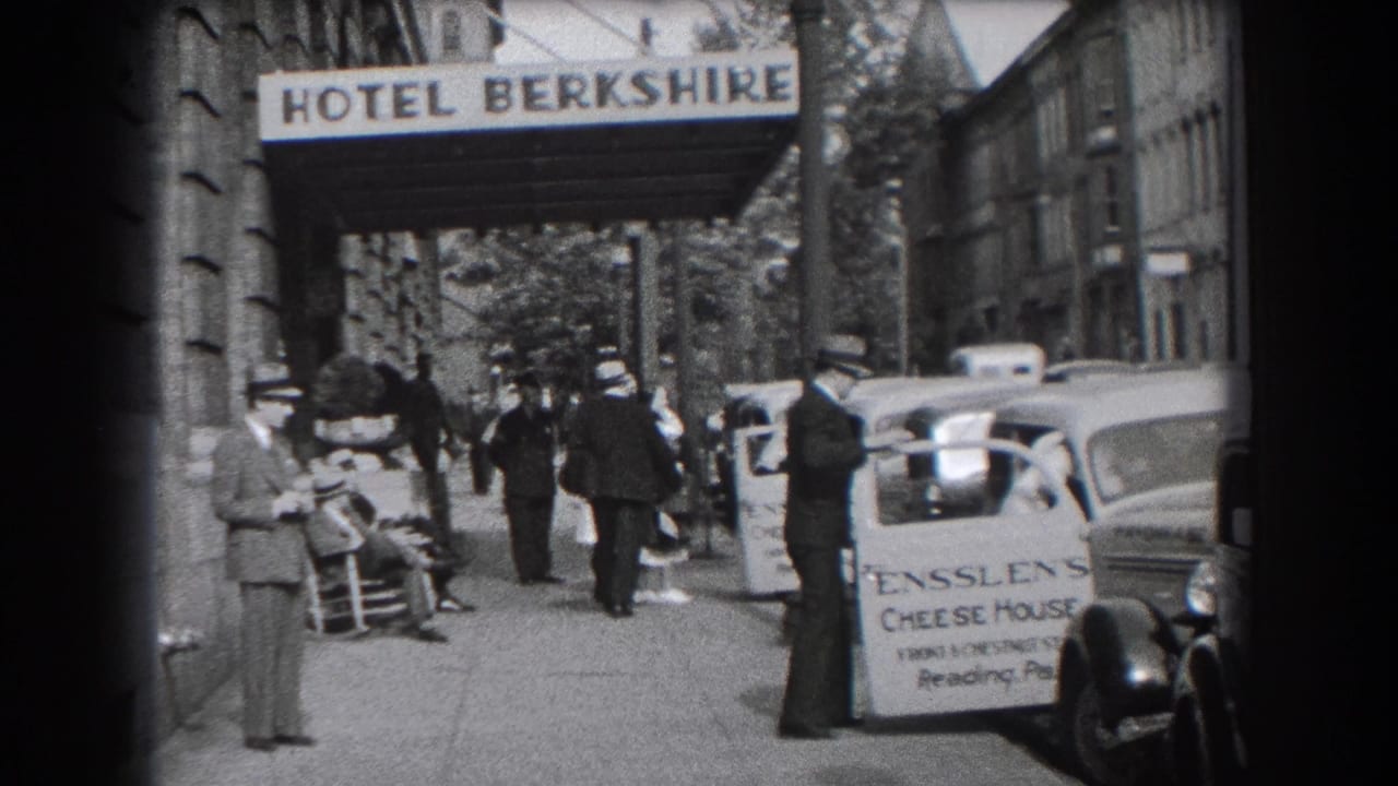 Hotel Berkshire awning above a busy sidewalk with pedestrians and cars near a curb sign.