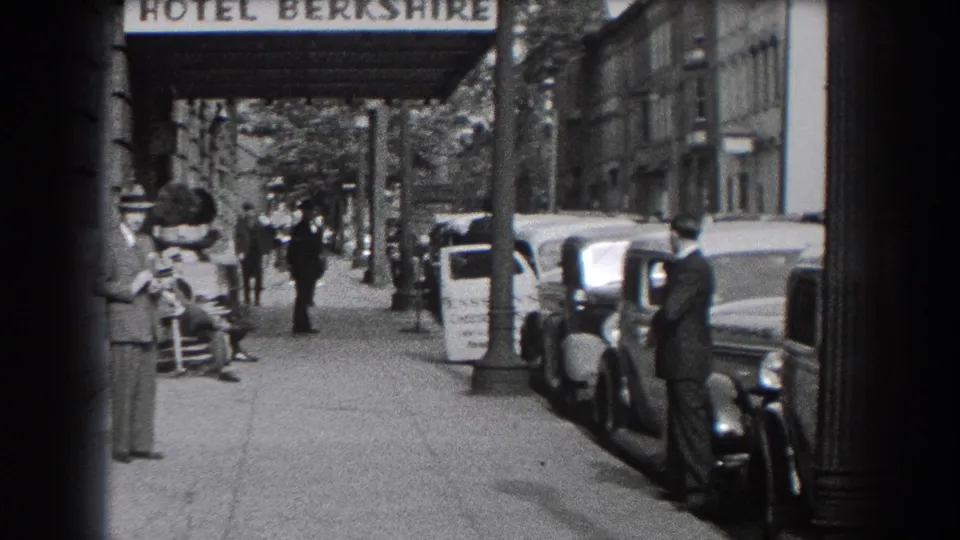 1938 Reading, Pennsylvania sidewalk view outside Hotel Berkshire with pedestrians, suited men, and vintage cars along the curb.