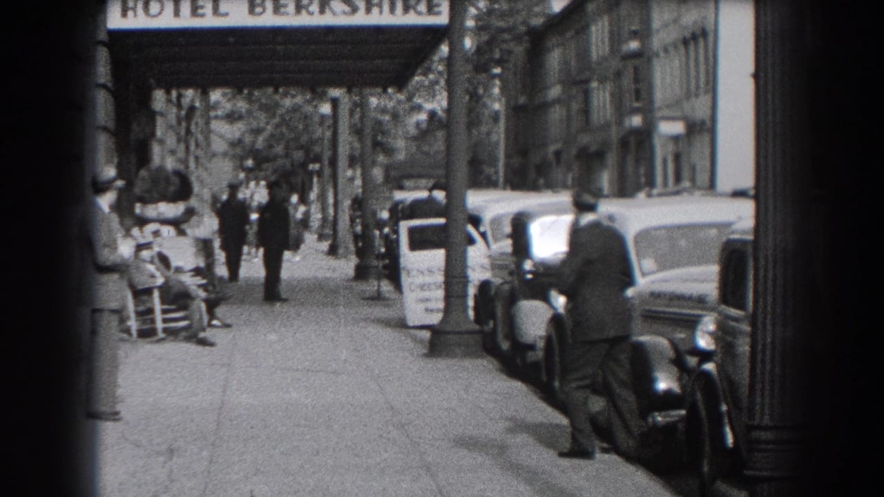 Reading street scene outside the Hotel Berkshire, showing pedestrians, vintage cars, and a man standing by a parked automobile.