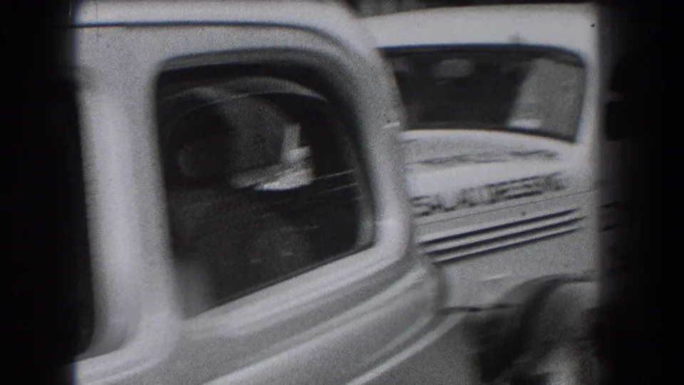 Close curbside frame of an Ensslen's Cheese House delivery van, with motion blur and surrounding 1930s street traffic.