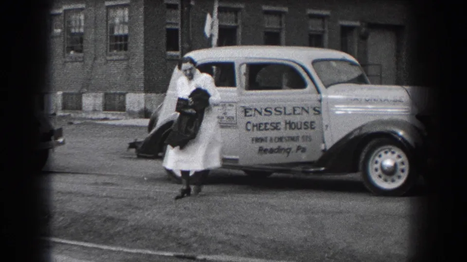 Two women in white uniforms are seen beside the Ensslen's Cheese House delivery car on a Reading, Pennsylvania street in 1938.