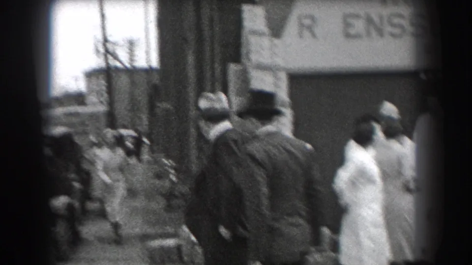In Reading, Pennsylvania, adults in 1930s clothing gather near a brick storefront with a partially visible R. Ensslen & Sons sign.