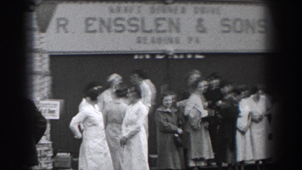 A group of adults stands in front of a storefront sign reading R. Ensslen & Sons.