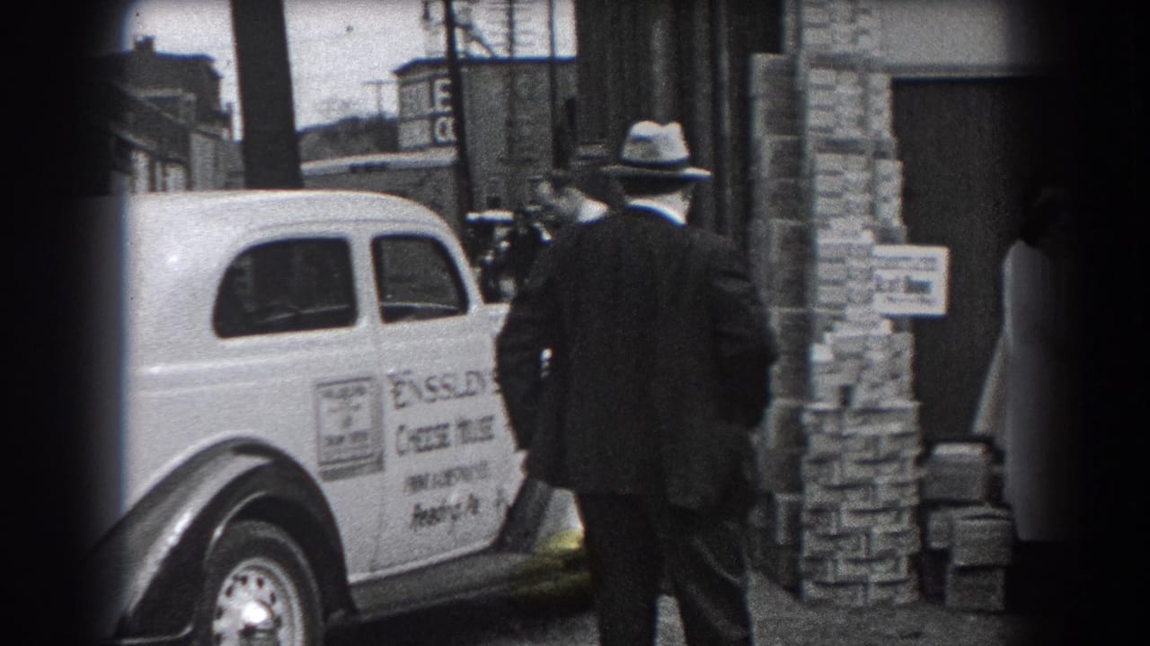 A Reading, Pennsylvania street view shows the Ensslen's Cheese House car beside a doorway, with a fedora-wearing man and bystanders nearby.