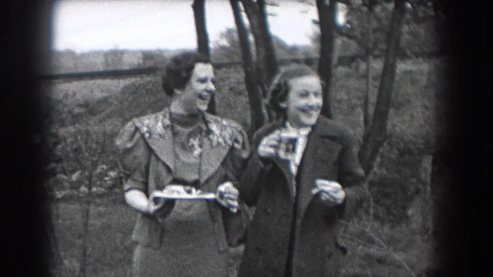 In 1938 Reading, Pennsylvania home-movie footage, two women stand outdoors smiling, with a tray and drinking glass visible.