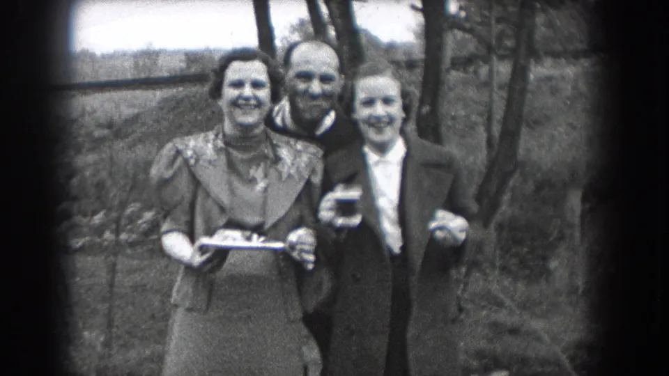 Three adults smile and pose outdoors in Reading, Pennsylvania, in a short 1938 8mm home-movie scene with drinks visible.