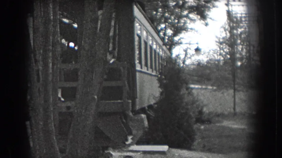 The camera holds on the house exterior, garden path, trees, and lamppost in the 1938 Reading backyard scene.