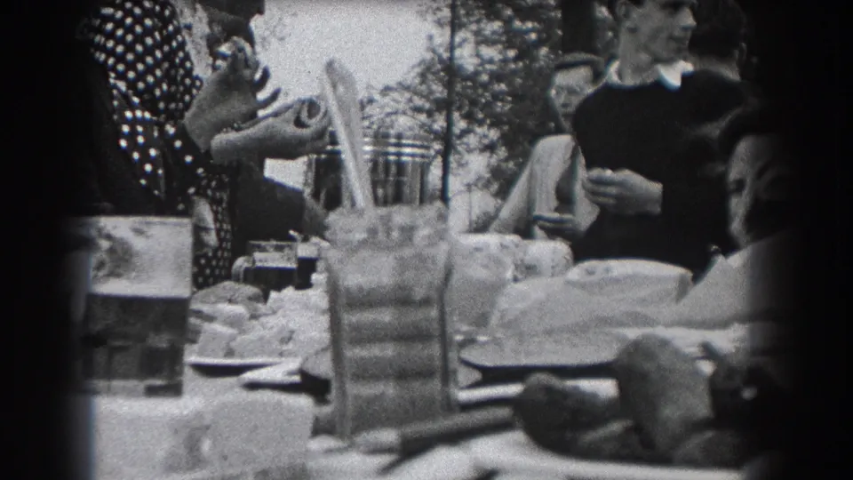 Party guests gather around a garden table with food and drinks in the 1938 Reading, Pennsylvania home movie.