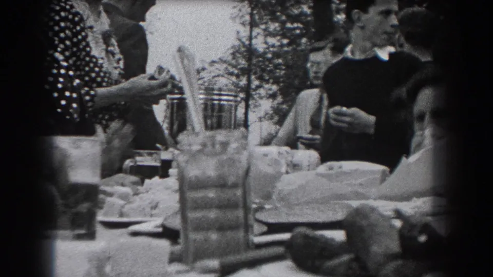 1938 Reading, Pennsylvania home-movie frame of adults at an outdoor meal, with a woman in a polka-dot dress near a table of dishes.