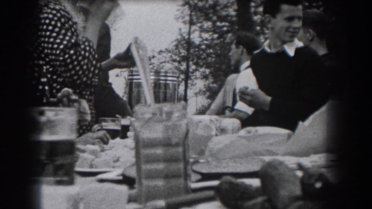 Adults at a 1938 outdoor meal in Reading, Pennsylvania, with a smiling man and nearby diners framed beside tableware and trees.