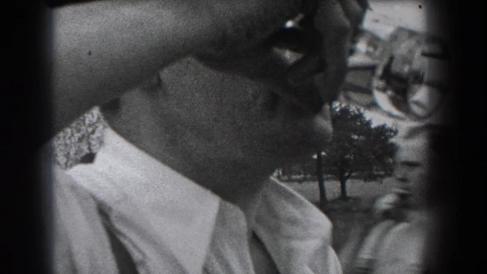 A close 1938 Reading, Pennsylvania frame shows the man tipping a glass bottle to his mouth in an outdoor setting.