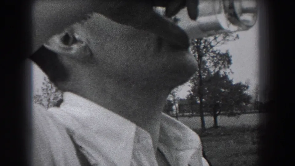 The man leans farther back while drinking from the bottle, with trees and open ground visible behind him in Reading, Pennsylvania.