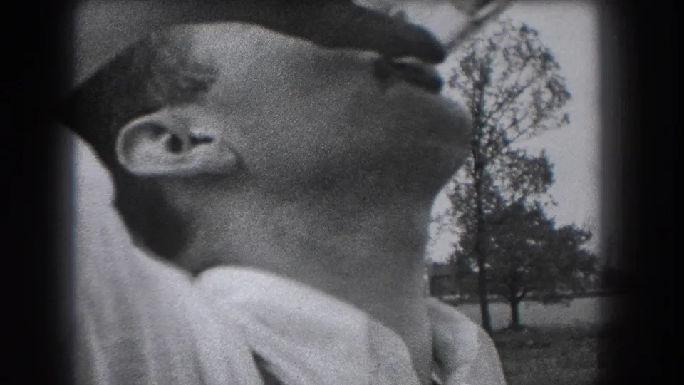 The final frame holds on the man with his head back and the bottle at his mouth during the 1938 outdoor home-movie scene.