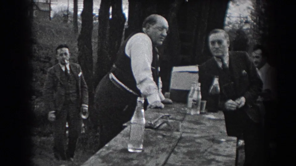 Reading, Pennsylvania home-movie frame from 1938 showing men in suits and vests beside an outdoor table with bottles.