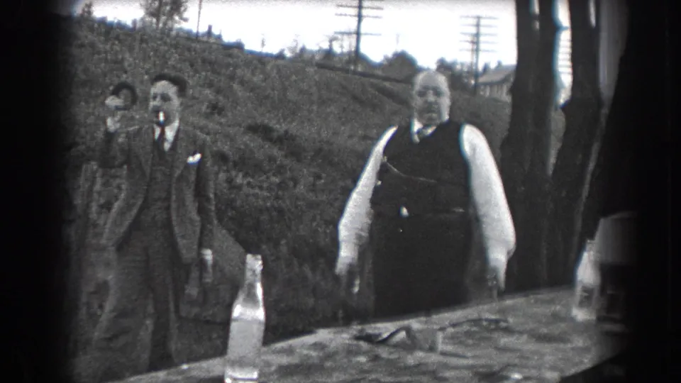 A 1938 Reading, Pennsylvania outdoor scene shows suited men socializing near a table, with one man smoking.