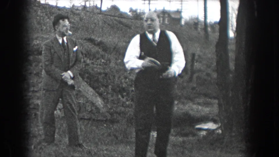 A 1938 Reading, Pennsylvania home-movie frame shows two men outdoors, with one holding an object near his vest.