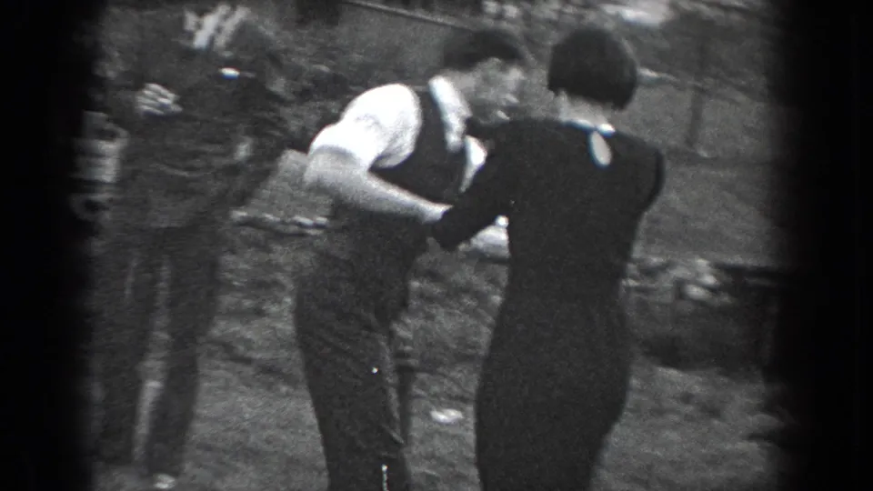 In this 1938 Reading, Pennsylvania home-movie frame, a couple dances outdoors on grass as formally dressed adults gather around them.