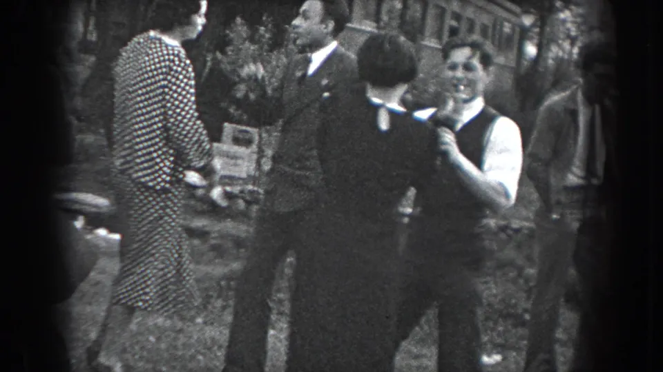 A group of adults at the 1938 Reading outdoor gathering stands near the dancers, including a man facing the camera and holding a cigarette.