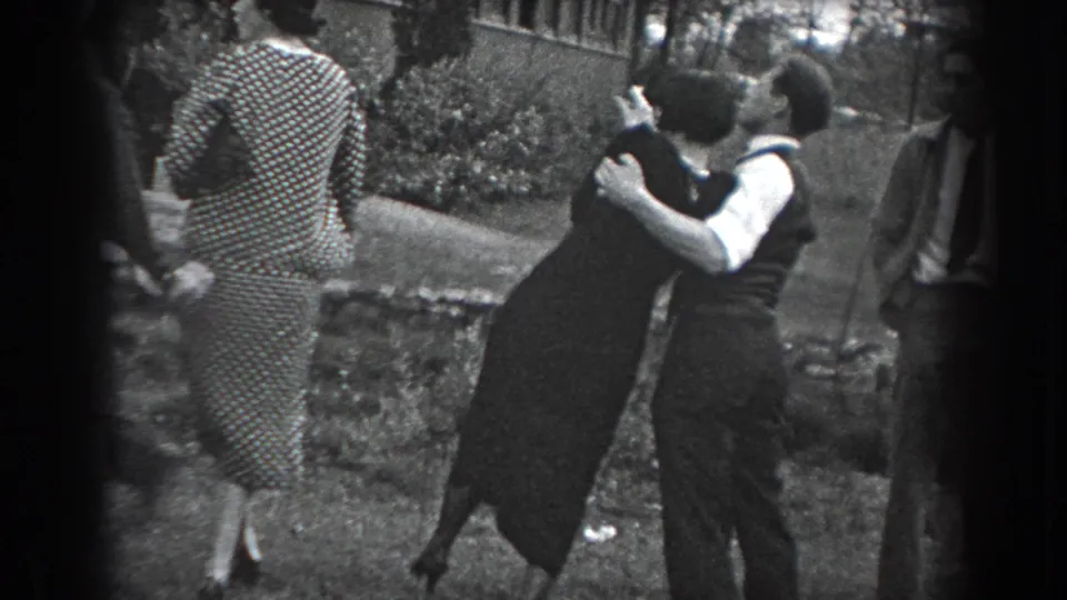 The dancing couple leans together on the lawn in Reading, Pennsylvania, with a woman in a patterned dress and other guests at the edge of frame.