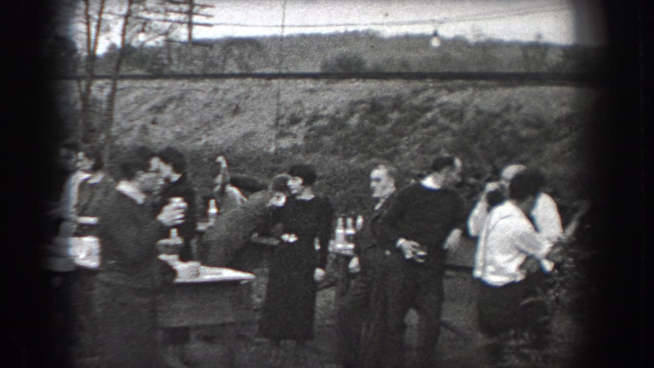 Group of adults stand around tables with drinks outdoors.