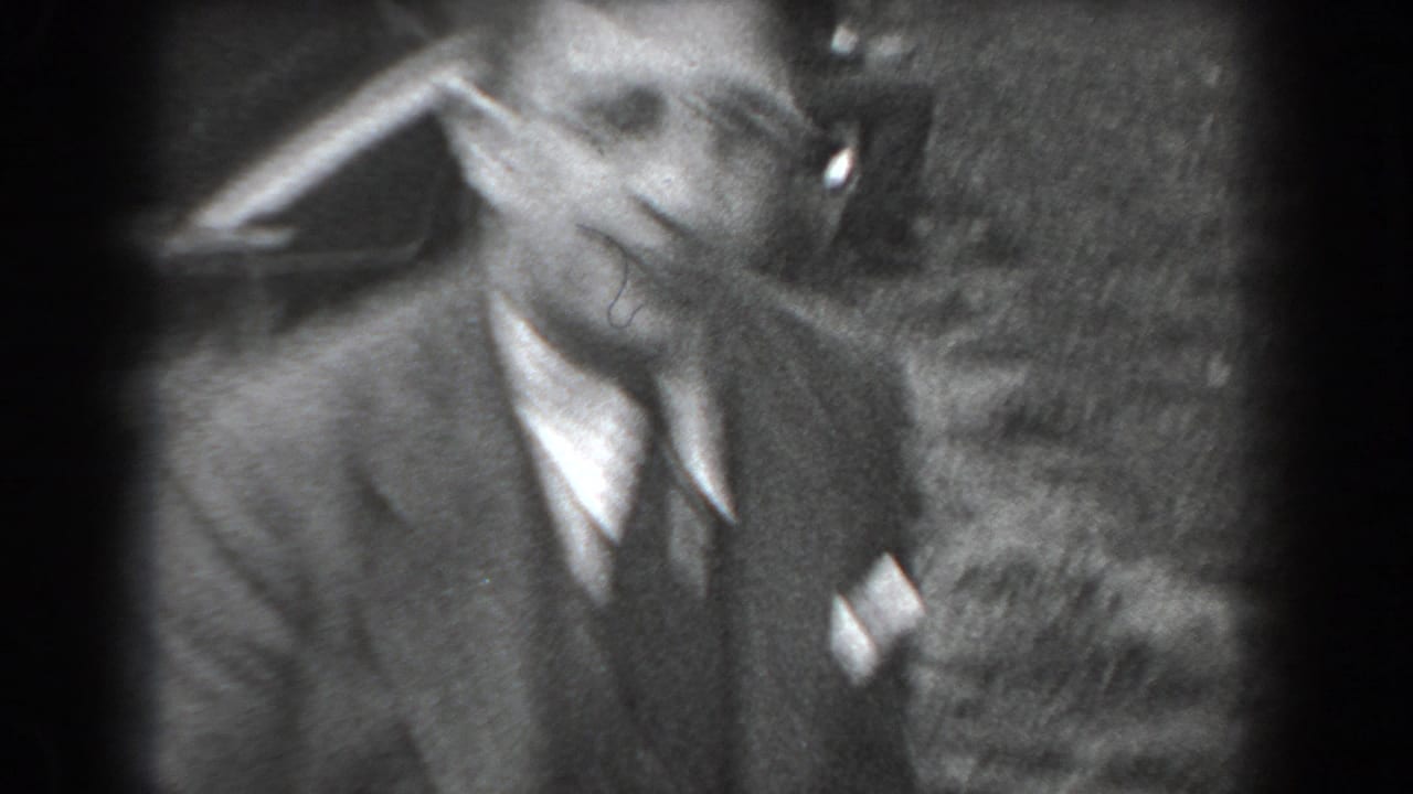 Closer view of a smiling man in a suit and tie outdoors.