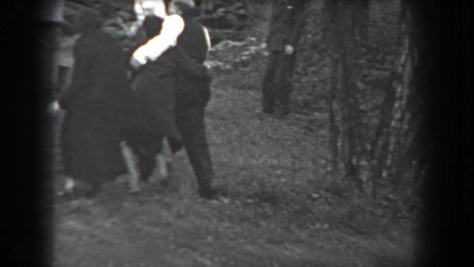 In Reading, Pennsylvania, 1938, adults in dark clothing gather outdoors while a woman in white gloves gestures toward the camera.