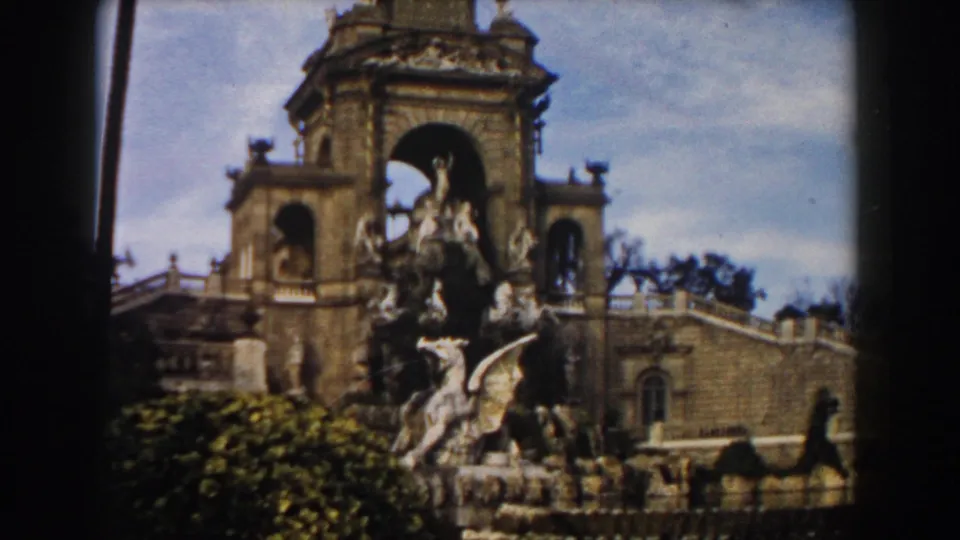1959 Barcelona frame showing the fountain's taller central structure, stone statues, formal hedges, and surrounding historic architecture.