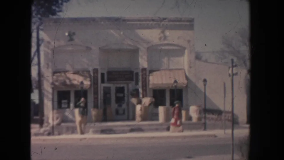 1951 New Mexico street view showing a small storefront with awnings, display windows, and a pedestrian walking along the sidewalk.