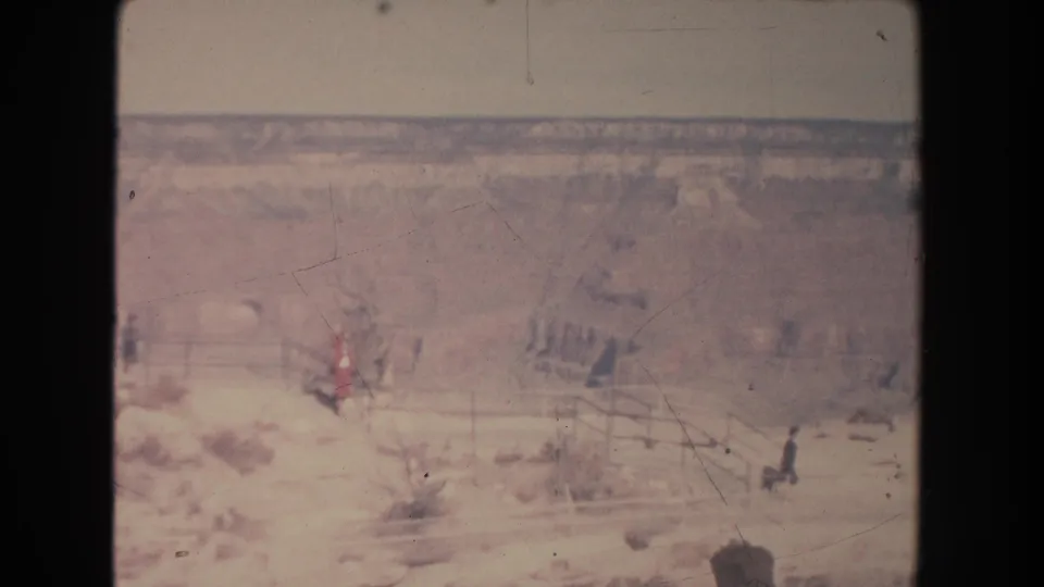 Wide 1951 New Mexico home-movie view of an arid overlook, railings, distant visitors, and a hazy desert or canyon landscape.