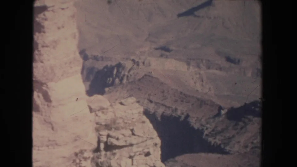 Close scenic view of pale canyon rock and a darker recess, with 8mm gate edge, scratches, and sun-faded color.