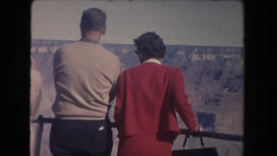 Back view of two adults at a 1951 New Mexico canyon lookout, with another person partly visible at the left edge.