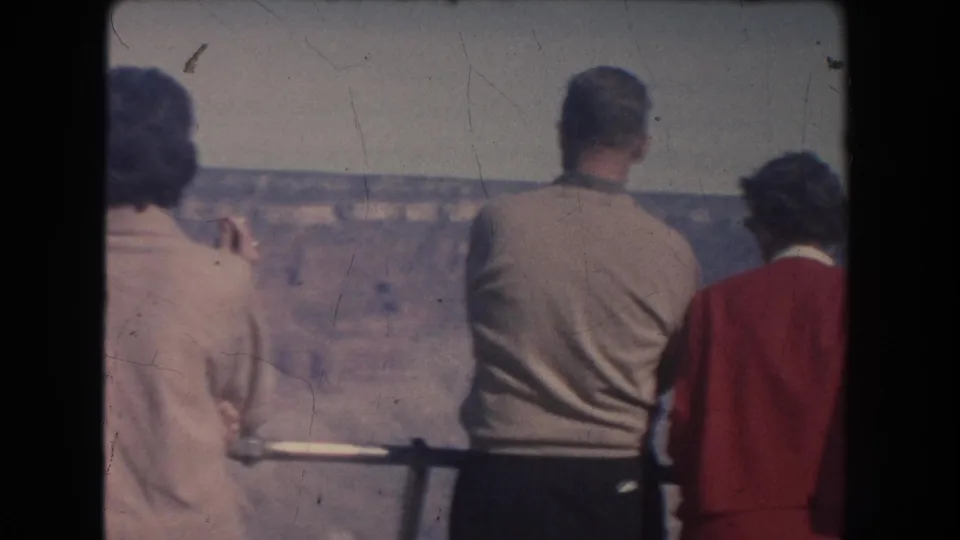Three adult visitors at a New Mexico canyon overlook in 1951, filmed from behind on faded 8mm color stock.