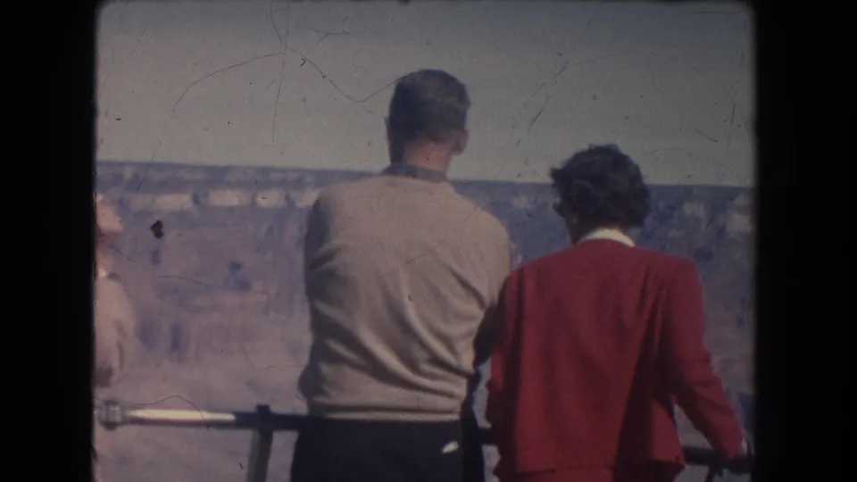 1951 home-movie frame of three visitors viewed from behind at a canyon overlook railing in New Mexico metadata.