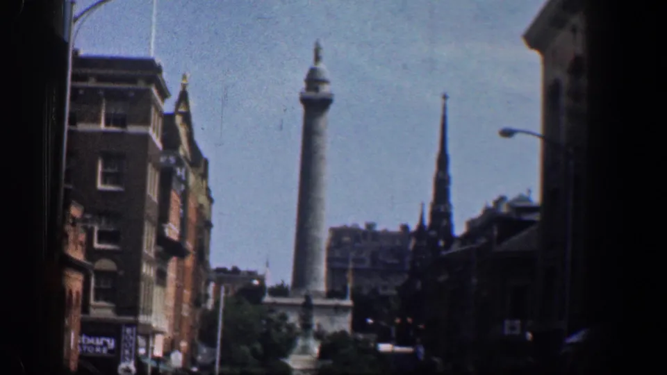 1961 Washington, DC frame with landmark architecture visible between brick buildings and street furniture.