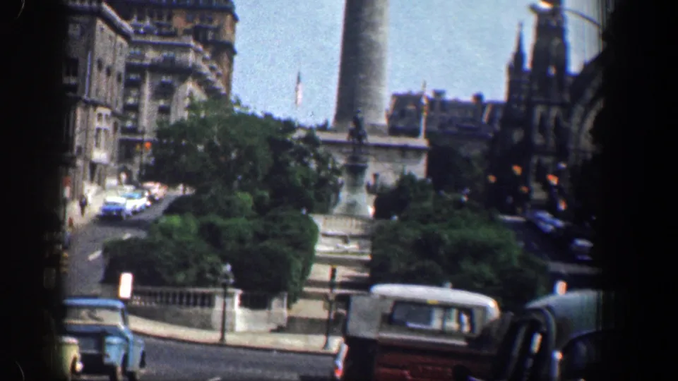 1961 Washington, DC street scene near the Washington Monument base, with classic cars, greenery, and stone architectural details.