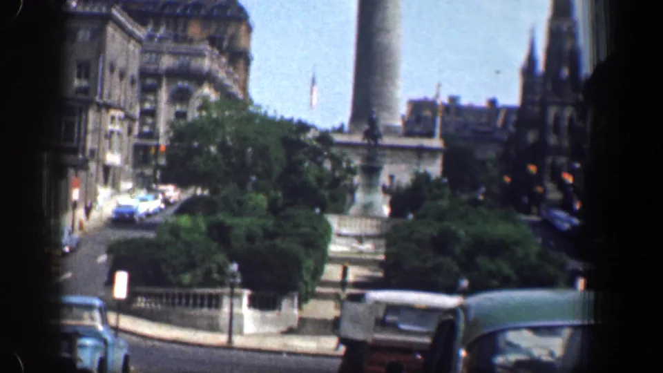 1961 Washington, DC traffic cutaway with cars, dense greenery, the Washington Monument, brick buildings, and a steeple.