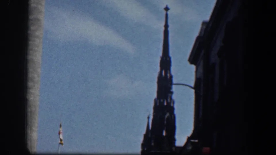 1961 Washington DC frame of a Gothic spire silhouetted against blue sky, with a dark building edge, streetlamp, and small flag visible below.