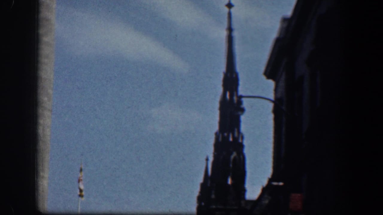 1961 Washington, DC home-movie frame showing a dark Gothic-style spire and nearby building edge against a blue sky.