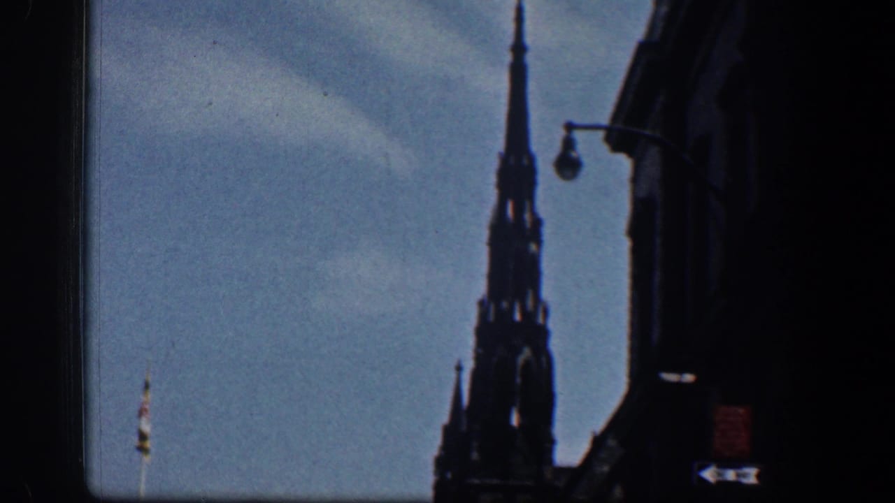 1961 Washington, DC frame with a Gothic-style spire, curved streetlamp, and dark building edge under blue sky.