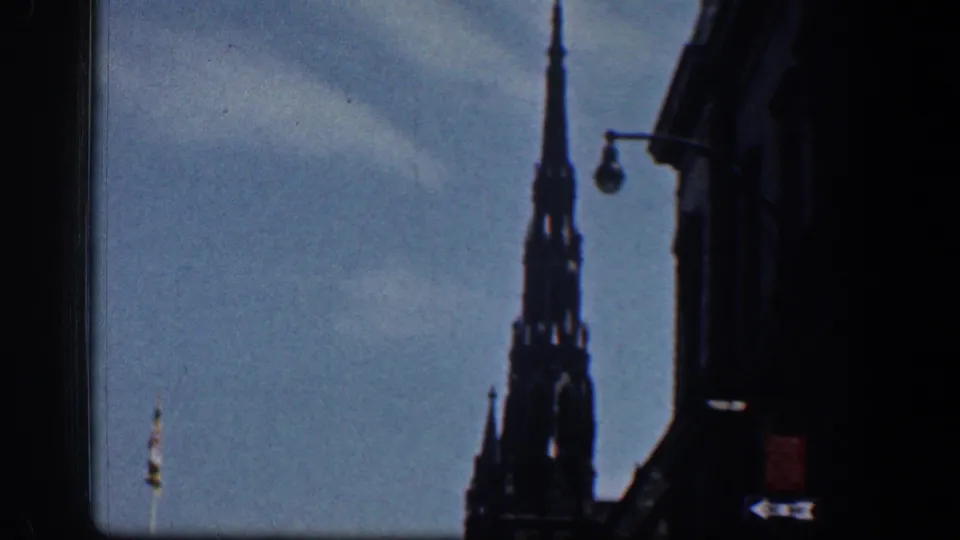 1961 Washington, DC frame with a Gothic-style spire, curved streetlamp, and dark building edge under blue sky.