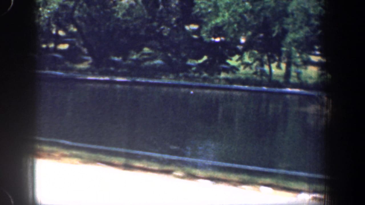 Car-window view of a broad, calm river with trees along the far bank in 1961 Washington, DC footage.