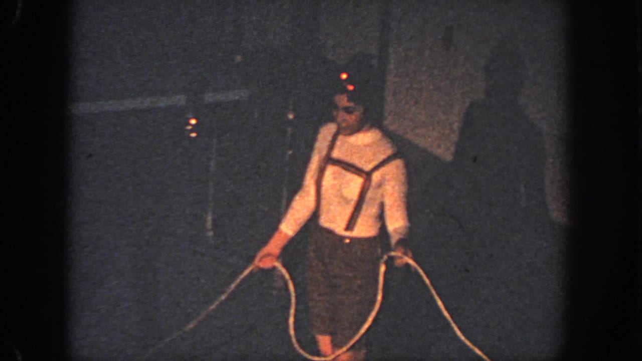 1951 Georgia home-movie frame with one visible swimmer in costume holding rope lines, with small red and green lights suggesting a reindeer role.