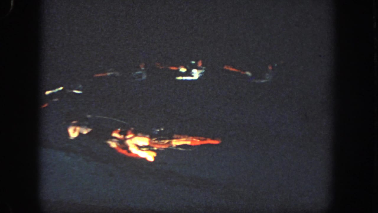 The frame shows paired synchronized swimmers in a dark Georgia pool, their red and white costume details lit by strong spotlights.