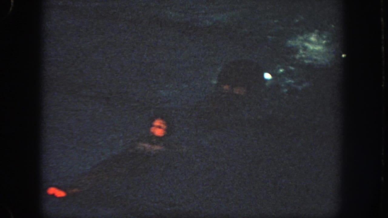Grainy 1951 Georgia 8mm frame showing a swimmer in dark pool water under low indoor lighting.