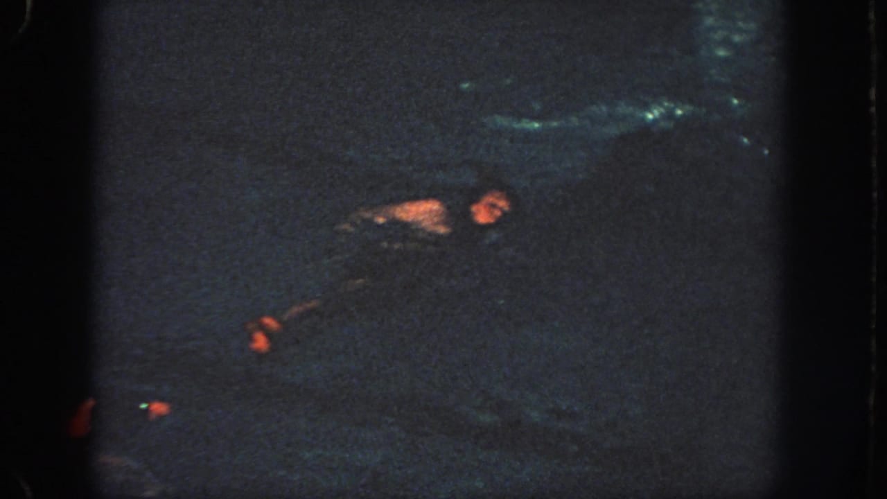 Low-light 8mm frame from Georgia in 1951 with a swimmer emerging in an indoor pool.