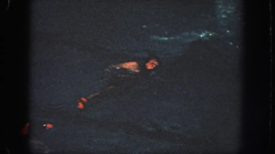 Low-light 8mm frame from Georgia in 1951 with a swimmer emerging in an indoor pool.