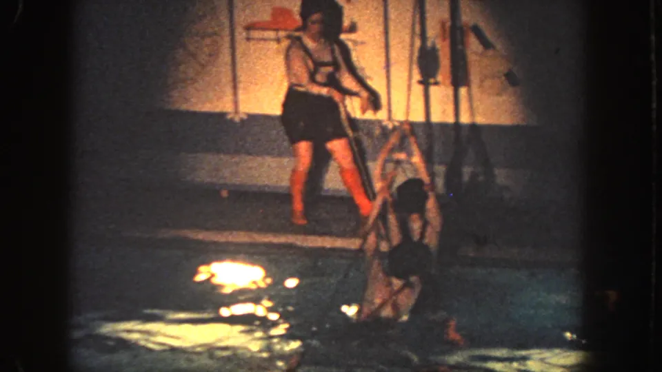 1951 Georgia home-movie frame showing a person at the pool edge and a swimmer climbing from the water.