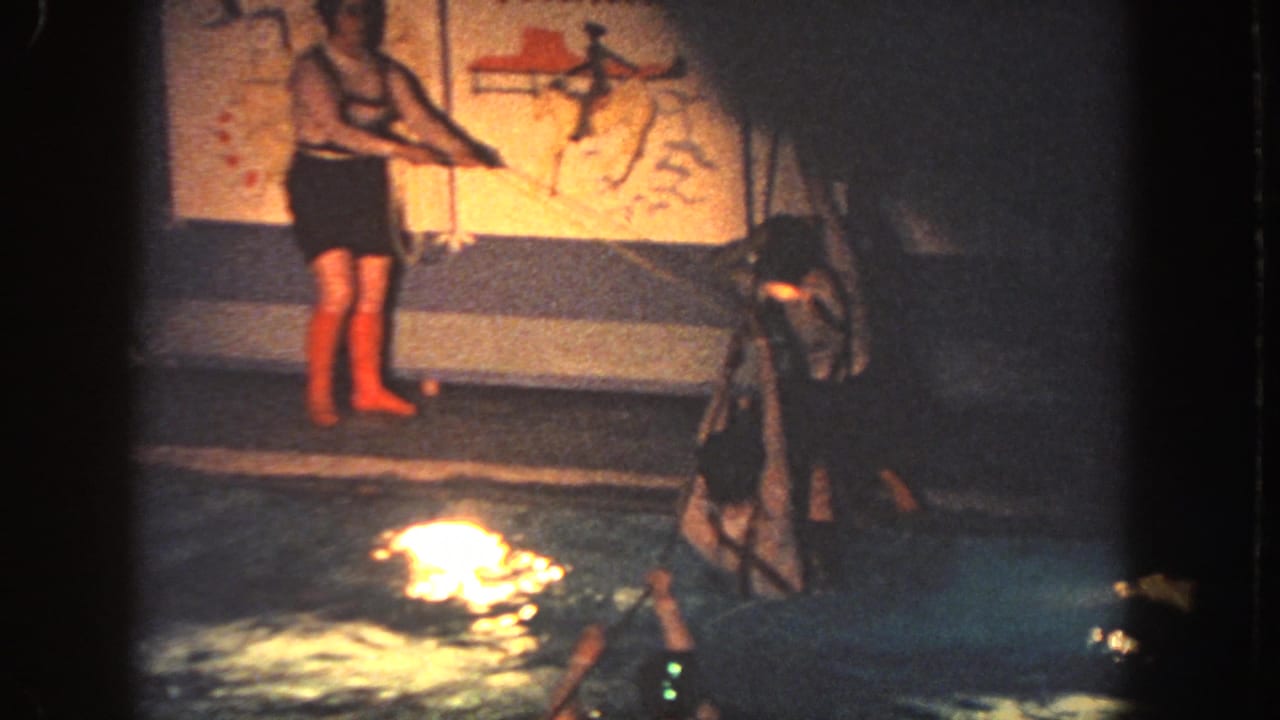 In 1951 Georgia home-movie footage, a girl in red boots watches participants move through a lit pool obstacle course.