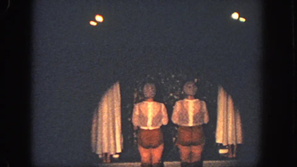 1951 Georgia 8mm frame of two performers in matching brown and white costumes on a dim stage.